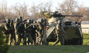 Russian troops take cover behind an armoured vehicle as they take over a Ukrainian airbase in Belbek
