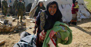 A Palestinian women from Arab al-Hazaleen (South Hebron) leave with their belongings 14 February 2007 as Israeli bulldozers demolish Bedouin mud houses beside the Israeli settlement of Karmel. AFP PHOTO/HAZEM BADER (Photo credit should read HAZEM BADER/AFP/Getty Images)