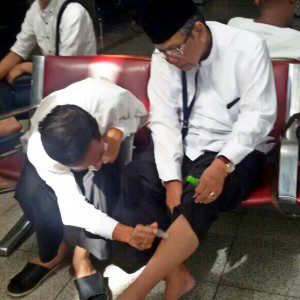 Jokowi sedang mengoleskan balsem cair ke kaki KH Hasyim Muzadi