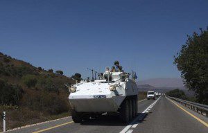 A member of UNDOF rides atop an armoured vehicle on Golan Heights