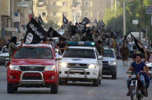 Militant Islamist fighters waving flags, travel in vehicles as they take part in a military parade along streets of Syria's northern Raqqa province