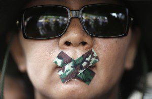 A woman with her mouth taped attends a protest against military rule in Bangkok