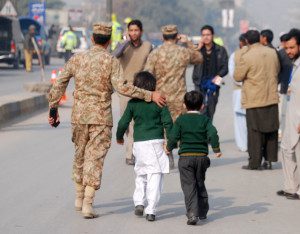 A soldier escorts schoolchildren after they were rescued from the Army Public School that is under attack by Taliban gunmen in Peshawar