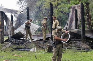 Indian security personnel inspect the debris of the houses that were burnt during attacks at Baksa district