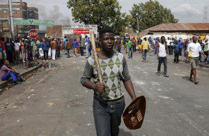 A local gestures as he holds a stick and a shield outside a hostel during anti-immigrant related violence in Johannesburg