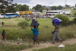 Foreigners from Zimbabwe carry their bags before boarding a bus home, from a camp for those affected by anti-immigrant violence in Chatsworth, north of Durban