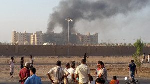 People watch as smoke billows from al-Qasr hotel after it was hit by explosions in the western suburbs of Yemen's southern port city of Aden