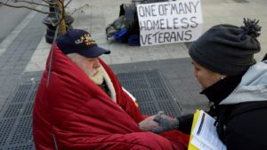 In this Wednesday, Nov. 20, 2013 photo, homeless Korean War veteran Thomas Moore, 79, left, speaks with Boston Health Care for the Homeless street team outreach coordinator Romeena Lee on a sidewalk in Boston. Moore, who said he accidentally killed his best friend with a phosphorous grenade during one firefight and spent months afterward at Walter Reed Army Medical Center in Washington, also said he has no interest in getting a government-subsidized apartment. (AP Photo/Steven Senne)
